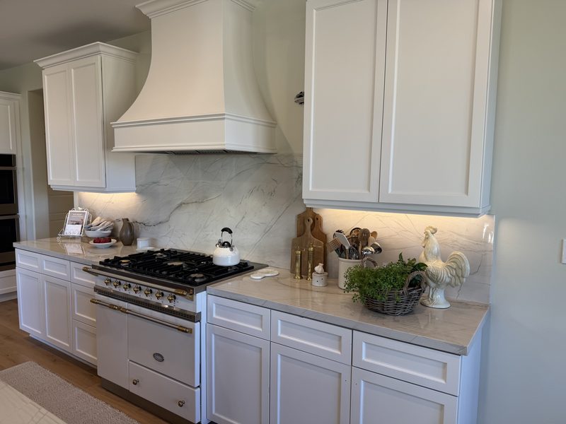 White kitchen with a plaster range hood, quartzite counters and a full slab backsplash
